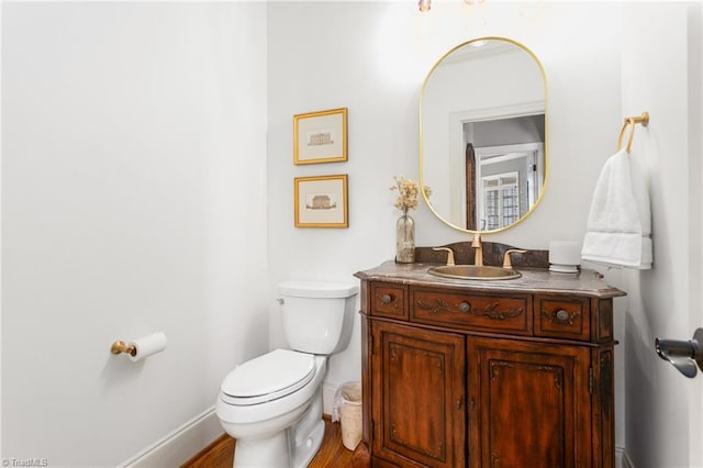 half bath featuring toilet, vanity, and baseboards