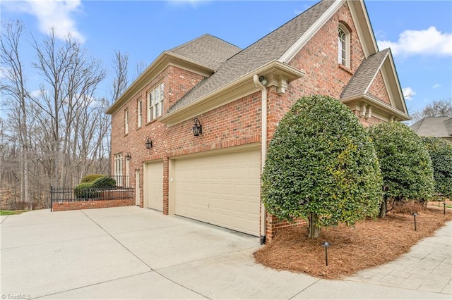 view of home's exterior featuring a garage, brick siding, concrete driveway, and a shingled roof