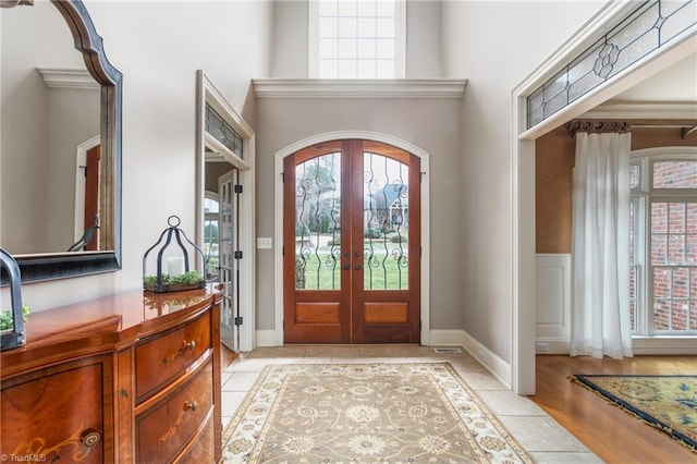 foyer entrance featuring light tile patterned flooring, a healthy amount of sunlight, french doors, and a high ceiling