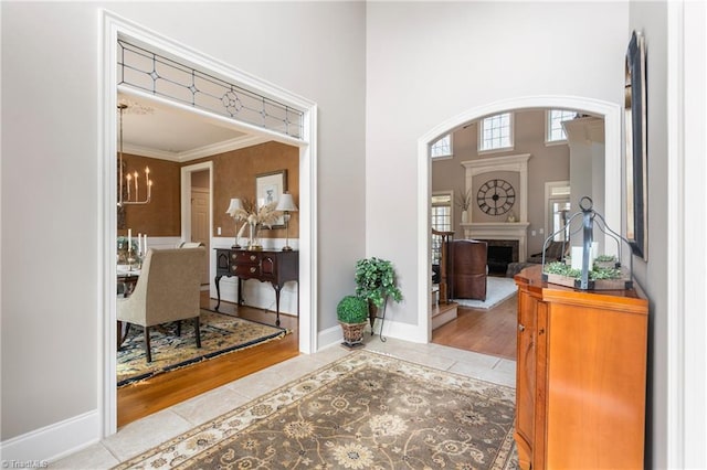 foyer entrance featuring tile patterned floors, a fireplace, a chandelier, baseboards, and a towering ceiling