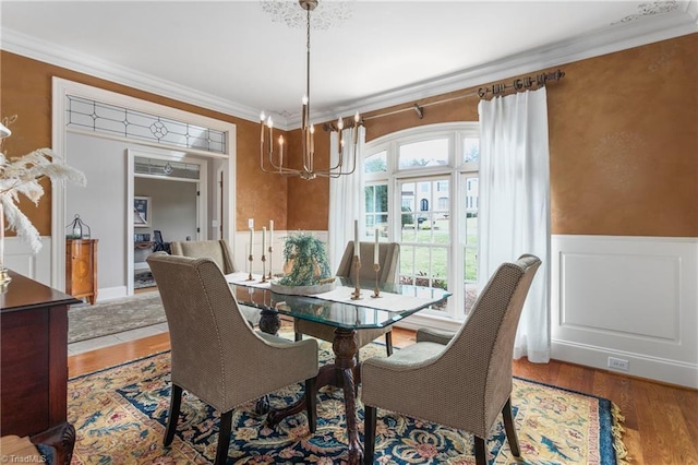 dining room with wood finished floors, wainscoting, and ornamental molding