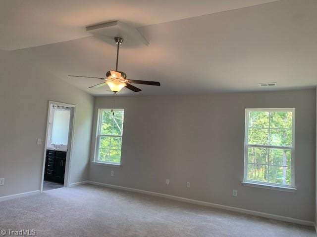 empty room with ceiling fan, light colored carpet, and vaulted ceiling