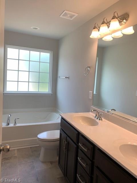 bathroom with tile patterned flooring, vanity, toilet, and a bath