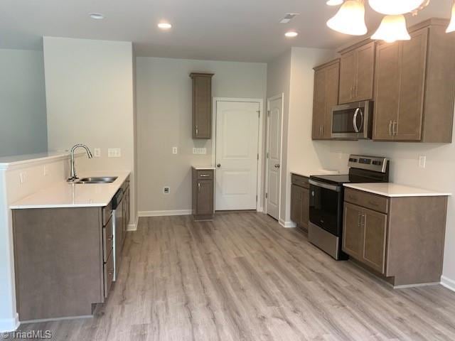 kitchen featuring appliances with stainless steel finishes, light hardwood / wood-style flooring, sink, and ceiling fan