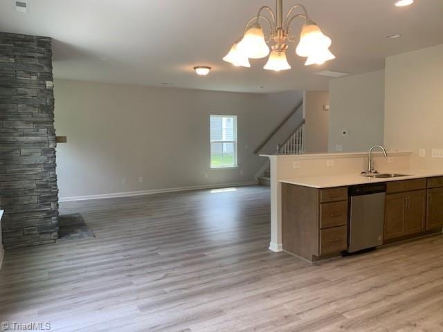 kitchen featuring pendant lighting, light hardwood / wood-style flooring, a notable chandelier, stainless steel dishwasher, and sink