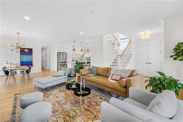 living area featuring an inviting chandelier, stairs, light wood finished floors, and recessed lighting
