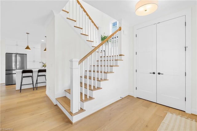 stairs with baseboards, wood finished floors, and recessed lighting