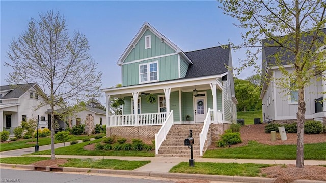 view of front facade with a ceiling fan, stairs, a front lawn, board and batten siding, and a porch