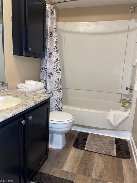 full bathroom featuring shower / bath combo with shower curtain, wood-type flooring, vanity, and toilet