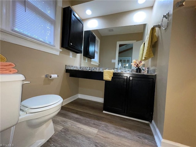 bathroom with toilet, vanity, and wood-type flooring