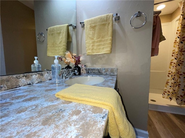 bathroom featuring walk in shower, vanity, and hardwood / wood-style flooring