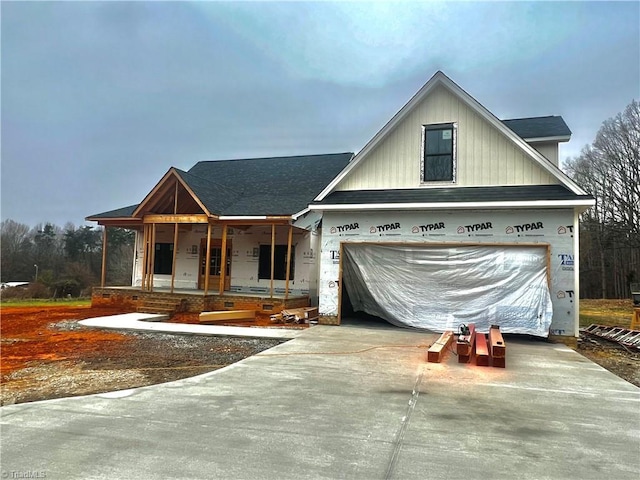 view of front facade featuring driveway, a porch, and roof with shingles