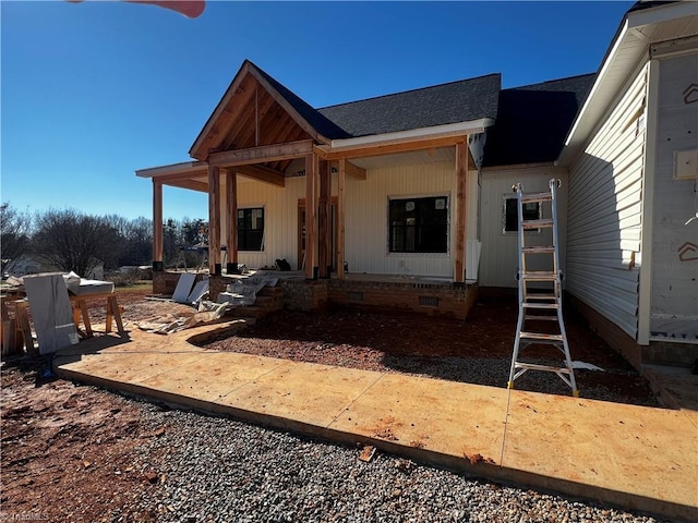 rear view of property featuring crawl space, a porch, and roof with shingles