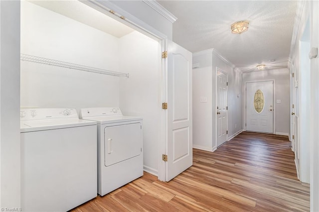 washroom with light wood finished floors, ornamental molding, washing machine and dryer, laundry area, and baseboards