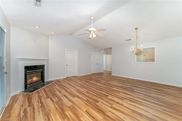 unfurnished living room with a fireplace, visible vents, light wood-style flooring, baseboards, and ceiling fan with notable chandelier