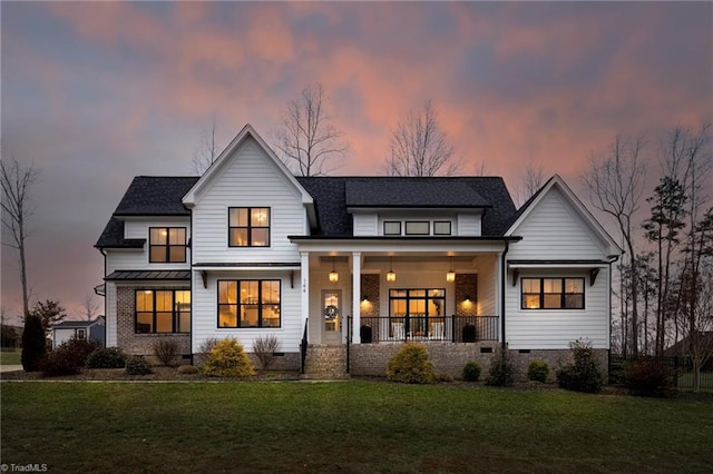 back of house at dusk featuring crawl space, a yard, and covered porch