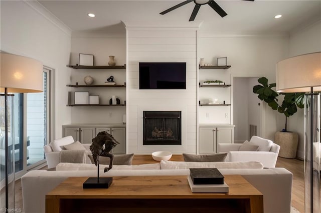 living area with crown molding, a ceiling fan, and wood finished floors