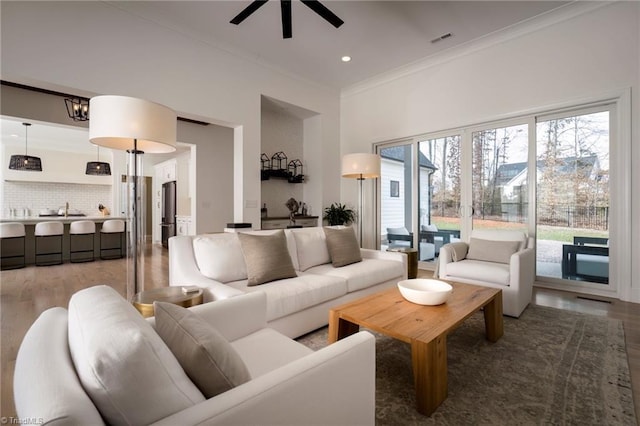 living room featuring visible vents, a ceiling fan, wood finished floors, recessed lighting, and crown molding