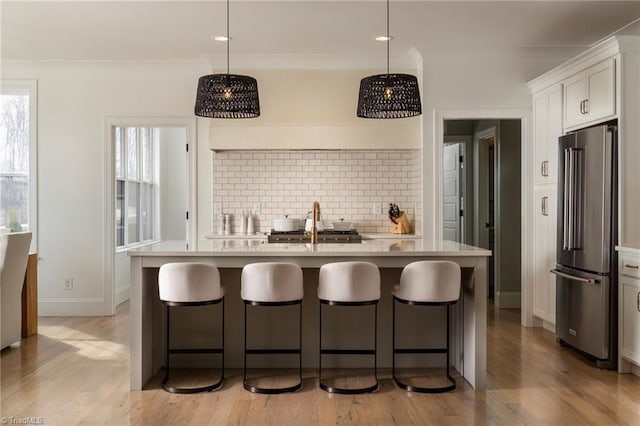 kitchen featuring backsplash, crown molding, high end refrigerator, and light countertops