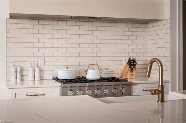 room details with white cabinetry, light stone counters, and tasteful backsplash