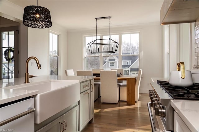 kitchen featuring wood finished floors, a sink, hanging light fixtures, light countertops, and a chandelier