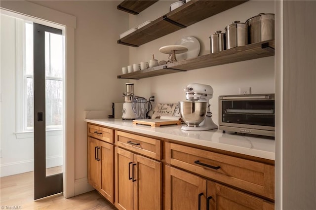 bar with a toaster, light wood-type flooring, and baseboards