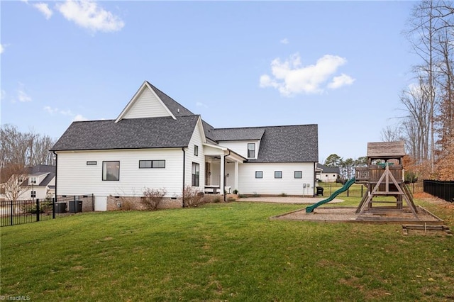 rear view of house with a yard, fence, a shingled roof, and a playground