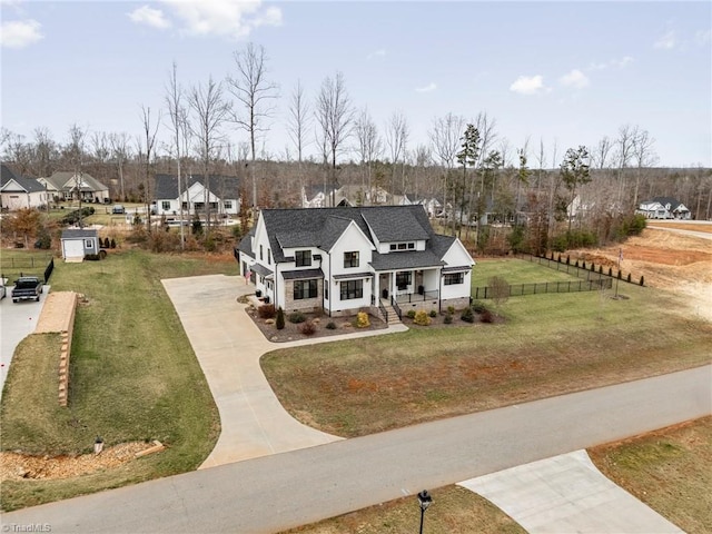 view of front of property featuring a front lawn, fence, concrete driveway, roof with shingles, and covered porch