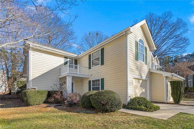 view of front of house featuring a front yard, a garage, and a balcony