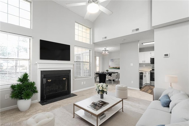 living room featuring ceiling fan, a high ceiling, and a wealth of natural light