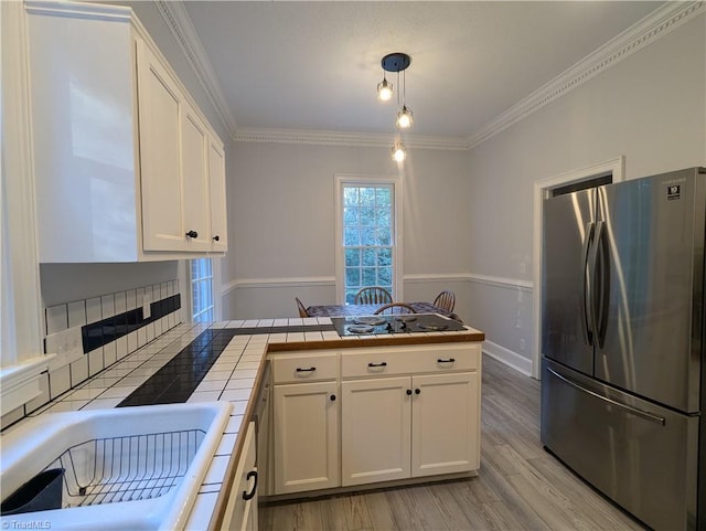 kitchen with tile countertops, white cabinets, pendant lighting, and stainless steel refrigerator