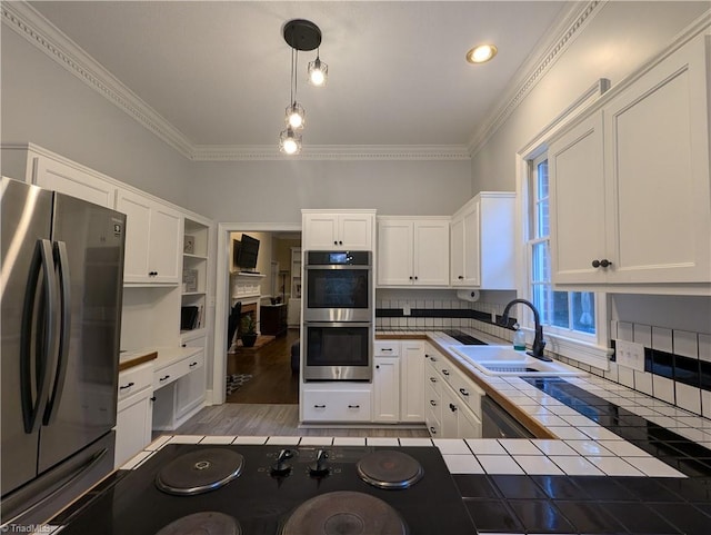 kitchen featuring appliances with stainless steel finishes, tile countertops, white cabinets, and decorative light fixtures