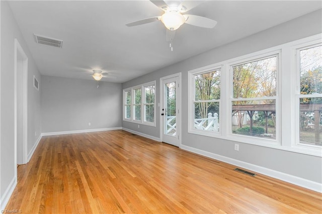 spare room with a wealth of natural light, ceiling fan, and light wood-type flooring