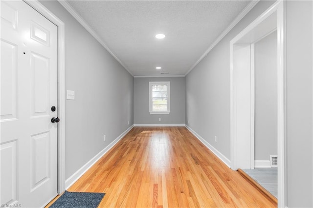 empty room with wood-type flooring, a textured ceiling, and ornamental molding