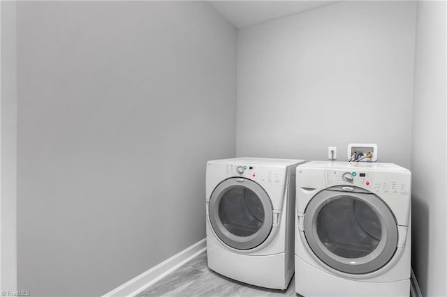 clothes washing area with washing machine and dryer and light wood-type flooring