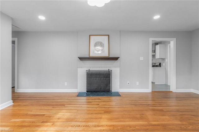 unfurnished living room with a brick fireplace and light hardwood / wood-style flooring