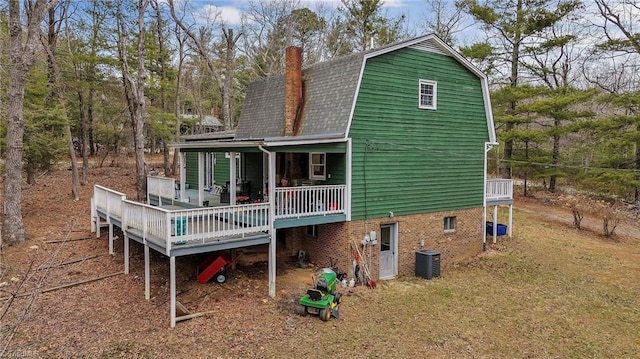 back of property with a gambrel roof, a wooden deck, central AC, roof with shingles, and a chimney