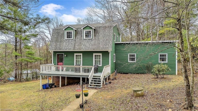 view of front facade with a wooden deck, a gambrel roof, and a shingled roof