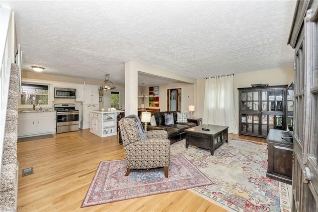 living room with light wood-type flooring, visible vents, and a textured ceiling