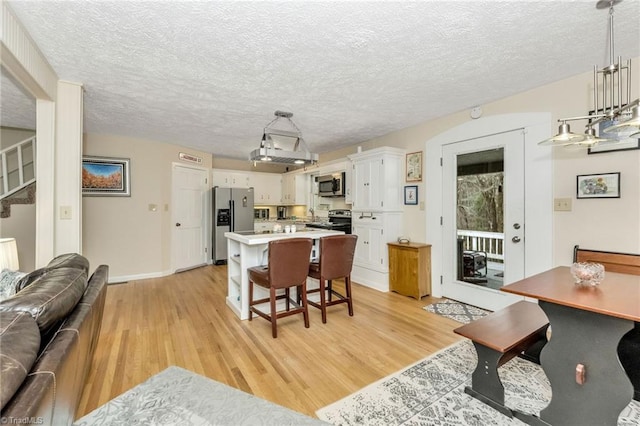 dining area featuring baseboards, a textured ceiling, stairs, and light wood finished floors