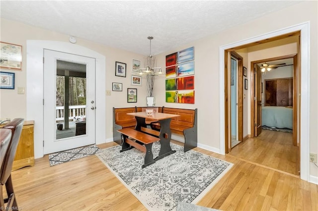 dining area with baseboards, light wood-style floors, and a textured ceiling