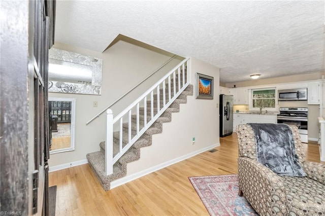 interior space with baseboards, a textured ceiling, and wood finished floors