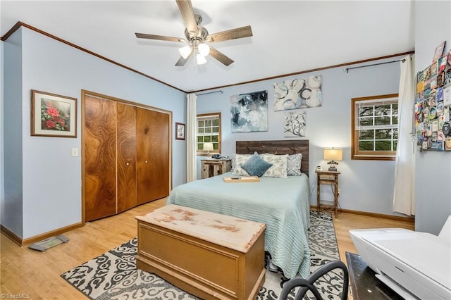 bedroom with a closet, light wood-style flooring, baseboards, and ornamental molding