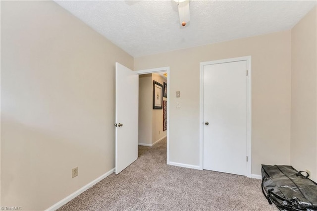 unfurnished bedroom with light colored carpet, baseboards, and a textured ceiling