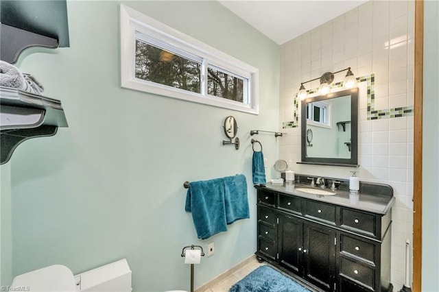 bathroom with tile patterned flooring, vanity, toilet, and tile walls