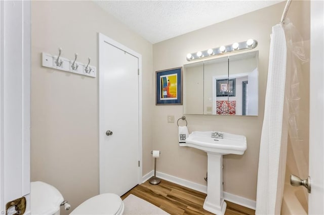 bathroom with toilet, a textured ceiling, wood finished floors, shower / bath combination with curtain, and baseboards