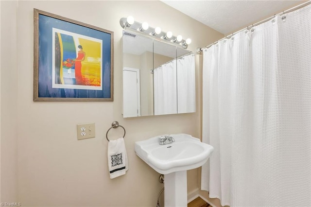 bathroom featuring a textured ceiling, a shower with shower curtain, and a sink