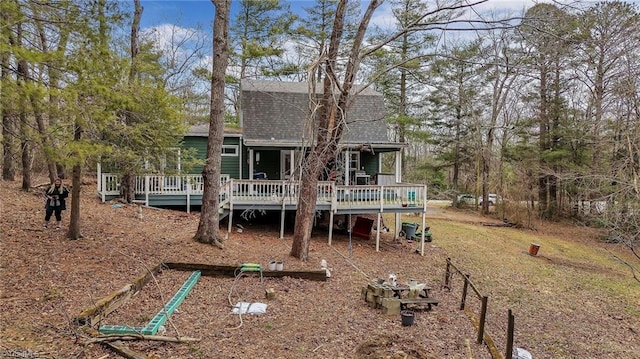 rear view of property with a wooden deck and a shingled roof