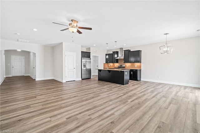 unfurnished living room featuring sink, wood-type flooring, and ceiling fan with notable chandelier