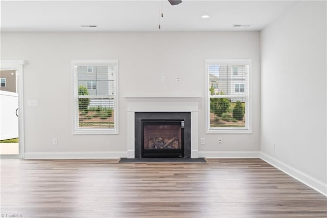 unfurnished living room featuring hardwood / wood-style flooring, ceiling fan, and a healthy amount of sunlight